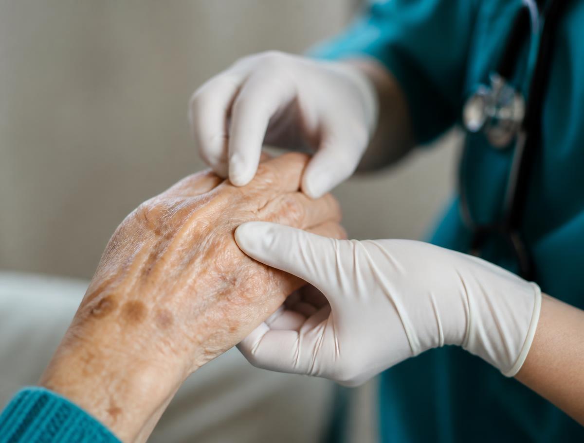 A clinician gently holding and examining an older adult's hand